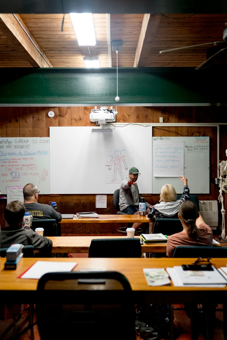 Instructor enseñando anatomía humana a adultos en escritorios de madera.